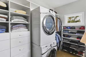 Laundry room featuring stacked washer / dryer and wood finished floors