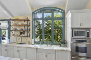 Interior space with white cabinets, open shelves, stainless steel appliances, light stone counters, and a warming drawer