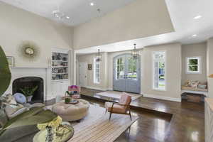 Living area with recessed lighting, dark wood-style flooring, a fireplace, built in shelves, and french doors