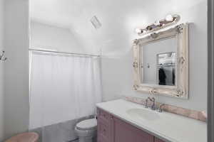 Bathroom featuring shower / bath combination with curtain, vanity, and vaulted ceiling