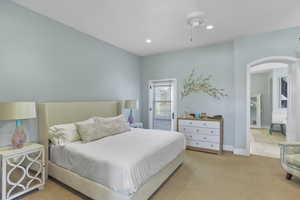 Bedroom featuring arched walkways, light carpet, access to exterior, recessed lighting, and a ceiling fan
