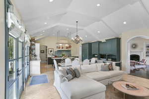 Living room featuring arched walkways, high vaulted ceiling, a chandelier, light tile patterned flooring, and recessed lighting