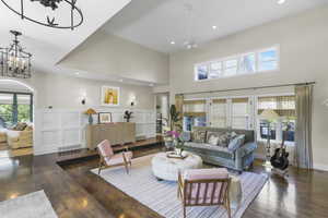 Living area with dark wood-style floors, recessed lighting, a towering ceiling, arched walkways, and a decorative wall