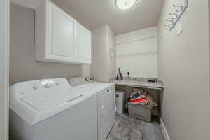 Laundry area with cabinet space, washer and clothes dryer, and a textured ceiling