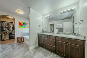 Bathroom with a bath, double vanity, and a spacious closet