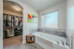 Bathroom featuring a garden tub and a walk in closet