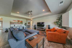 Living area with arched walkways, a tray ceiling, recessed lighting, and ceiling fan
