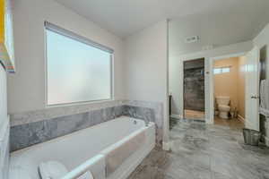 Bathroom featuring a garden tub and a tile shower