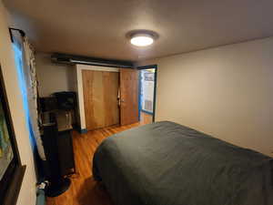 Bedroom with light wood-style floors, a textured ceiling, and a closet