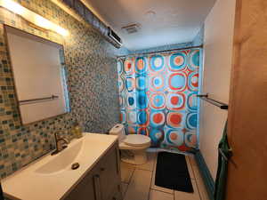 Full bath featuring light tile patterned flooring, vanity, a textured ceiling, and tile walls