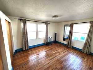 Spare room with a textured ceiling, healthy amount of natural light, dark wood finished floors, and a baseboard radiator