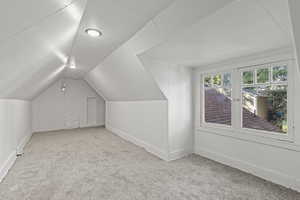 Bonus room with light colored carpet and lofted ceiling