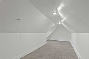 Additional living space featuring light colored carpet and lofted ceiling
