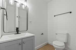 Half bathroom with vanity, quartz countertops, and light wood-style floors