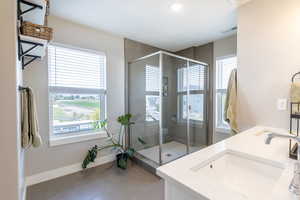 Bathroom with double vanity, light tile patterned flooring, a shower stall, and recessed lighting