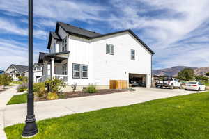 View of side of home with board and batten siding, covered porch, concrete driveway, a mountain view, and a garage