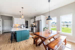 Kitchen with white cabinetry, a center island with sink, a breakfast bar area, light wood-style flooring, and stainless steel appliances