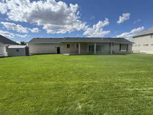 Rear view of house with a storage shed, brick siding, and a patio