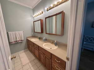 Bathroom featuring double vanity, crown molding, and light tile patterned floors