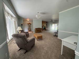 Living room featuring carpet, a textured ceiling, a chandelier, crown molding, and a ceiling fan