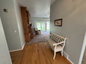 Hallway featuring light wood-type flooring and a textured ceiling