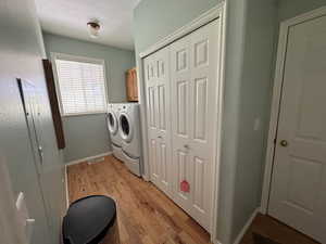 Laundry area with light wood finished floors, separate washer and dryer, and cabinet space