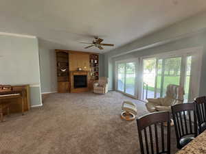 Living room with a fireplace, carpet, and ceiling fan