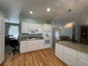 Kitchen featuring decorative light fixtures, a chandelier, white cabinets, and recessed lighting