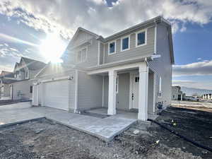 View of front of house featuring a porch, concrete driveway, and an attached garage