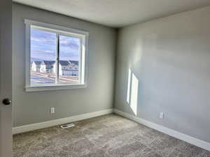 Carpeted spare room with baseboards and a textured ceiling