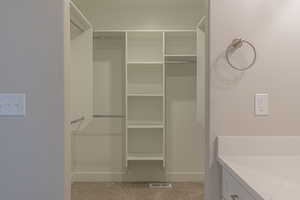 Walk in closet featuring light colored carpet