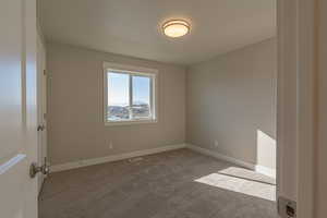 Carpeted empty room featuring baseboards