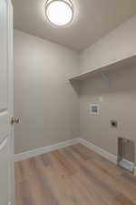 Laundry room with a textured ceiling, light wood-style flooring, hookup for a washing machine, and hookup for an electric dryer