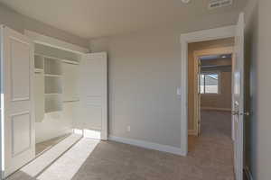 Unfurnished bedroom with light carpet and a closet