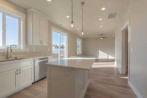 Kitchen featuring white cabinets, decorative light fixtures, recessed lighting, stainless steel dishwasher, and light wood-style flooring