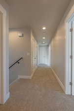 Hallway with light carpet, recessed lighting, and an upstairs landing