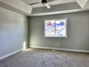 Unfurnished room with a textured ceiling, a raised ceiling, carpet flooring, and a ceiling fan