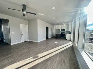 Unfurnished living room featuring dark wood-style floors, a ceiling fan, and recessed lighting
