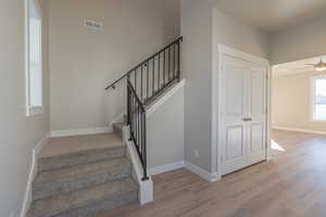 Staircase featuring wood finished floors and ceiling fan