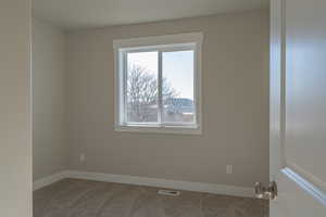 Carpeted spare room with baseboards