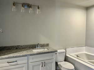 Full bathroom with vanity, a garden tub, and a textured ceiling