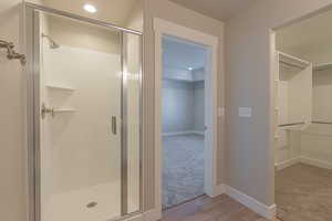 Bathroom with a stall shower, light wood-style flooring, a spacious closet, and recessed lighting