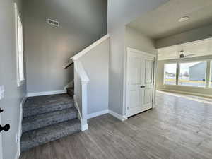 Stairs with a ceiling fan, wood finished floors, and a textured ceiling