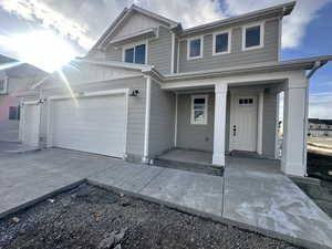 View of front of home with covered porch, board and batten siding, driveway, and an attached garage