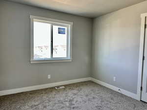 Carpeted empty room featuring baseboards and a textured ceiling