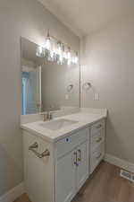 Bathroom with vanity, dark wood-style floors, and a textured ceiling