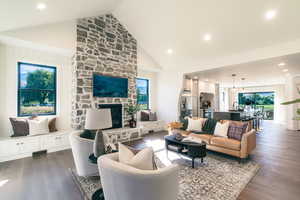 Living room featuring dark wood-style flooring, high vaulted ceiling, recessed lighting, and a fireplace