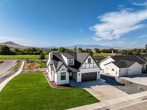 View of front of home with a garage, driveway, a mountain view, and a front lawn