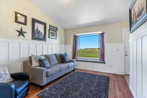 Living room with a decorative wall, a wainscoted wall, and wood finished floors