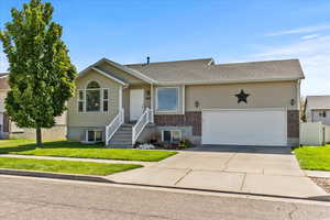 Ranch-style home with a front yard, concrete driveway, brick siding, and an attached garage